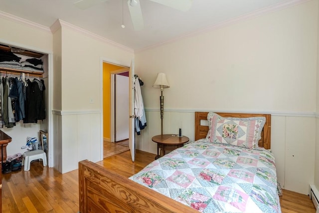 290 E St, Westwood, MA 02090 - bedroom featuring wood finished floors, a wainscoted wall, a baseboard radiator, a closet, and crown molding