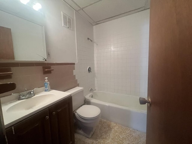 full bathroom with vanity, toilet, tile walls, and tiled shower / bath