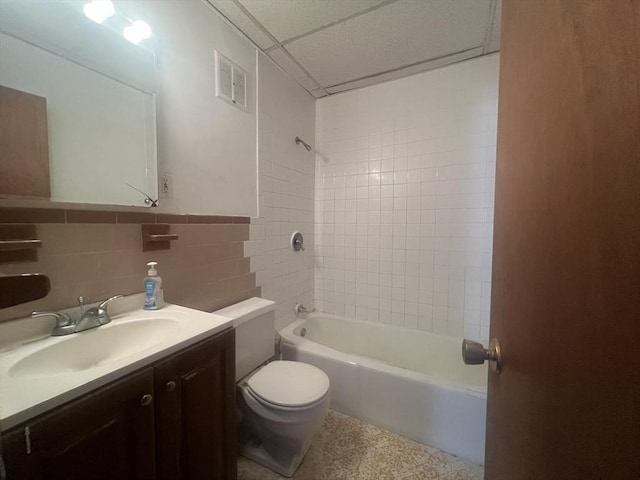 full bathroom featuring tile walls, tiled shower / bath, vanity, and toilet