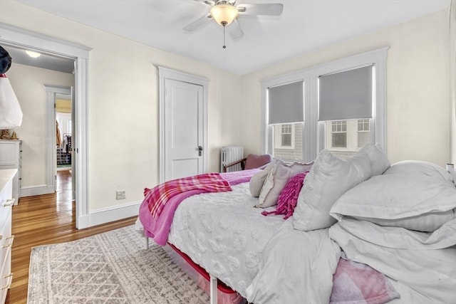 bedroom featuring ceiling fan, radiator heating unit, and light hardwood / wood-style floors