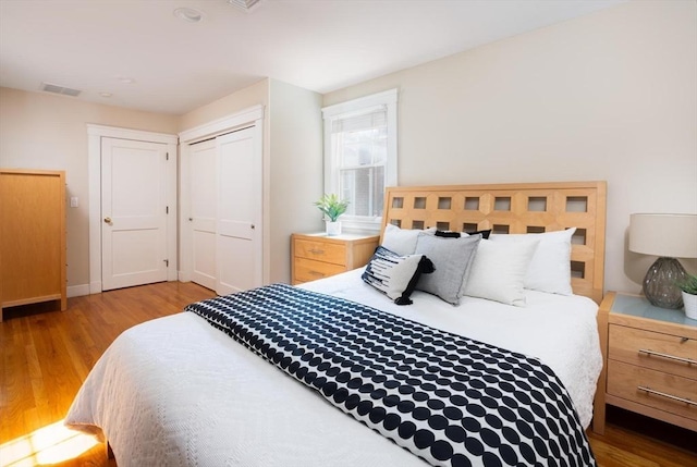 bedroom with wood finished floors, a closet, and baseboards