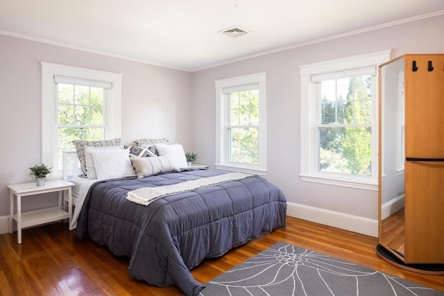 bedroom featuring multiple windows, baseboards, ornamental molding, and wood finished floors