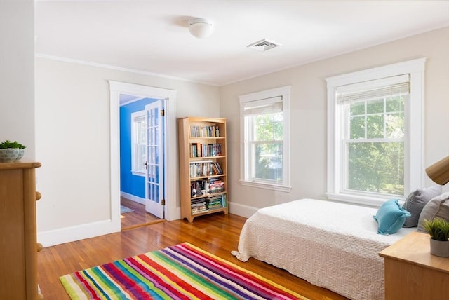 bedroom with baseboards, wood finished floors, and ornamental molding