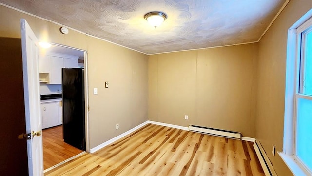 spare room with a baseboard heating unit, light hardwood / wood-style floors, and a textured ceiling