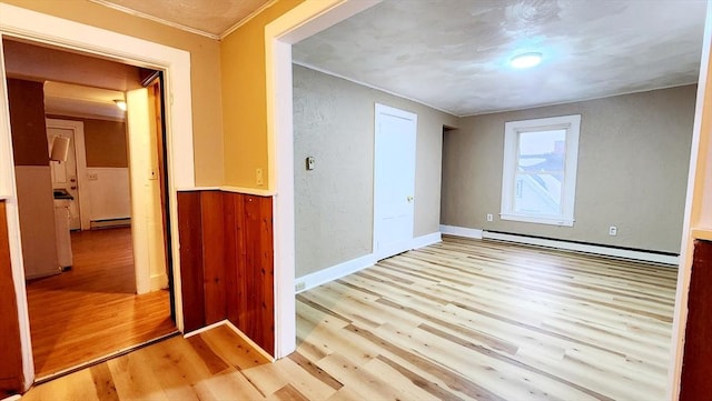 spare room with baseboard heating and light hardwood / wood-style floors