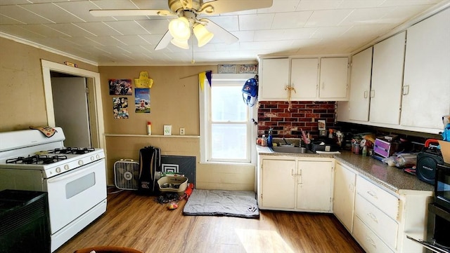 kitchen featuring white cabinetry, sink, white gas stove, ornamental molding, and light wood-type flooring