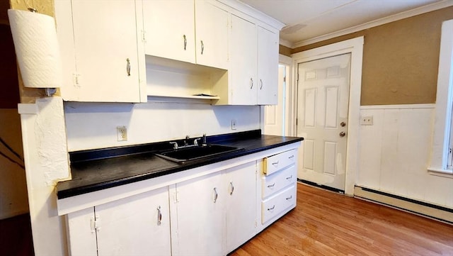 kitchen featuring crown molding, a baseboard radiator, sink, white cabinetry, and light hardwood / wood-style floors