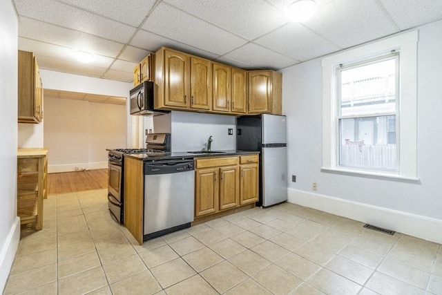 kitchen featuring sink, light tile patterned floors, a paneled ceiling, and stainless steel appliances