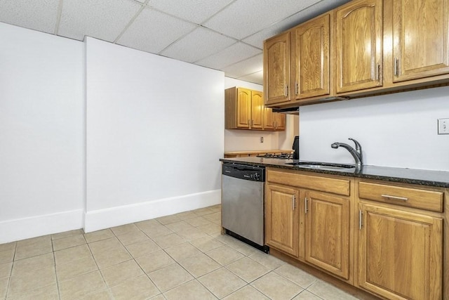 kitchen featuring dishwasher, sink, a paneled ceiling, dark stone counters, and light tile patterned floors