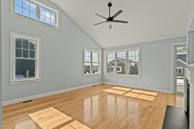 unfurnished living room with high vaulted ceiling, ceiling fan, and light wood-type flooring