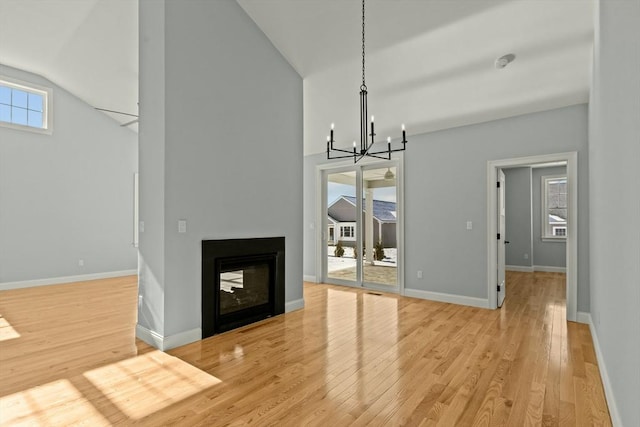 unfurnished living room with light hardwood / wood-style floors, a chandelier, and a multi sided fireplace