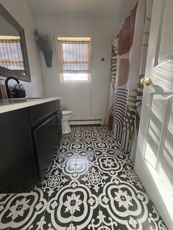 full bathroom featuring tile patterned floors, baseboard heating, toilet, and vanity