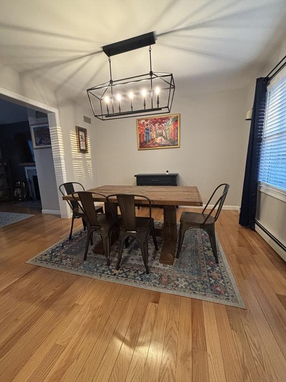 dining room with visible vents, baseboards, wood finished floors, and a baseboard radiator