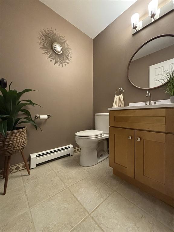 bathroom featuring a baseboard heating unit, toilet, vanity, and vaulted ceiling