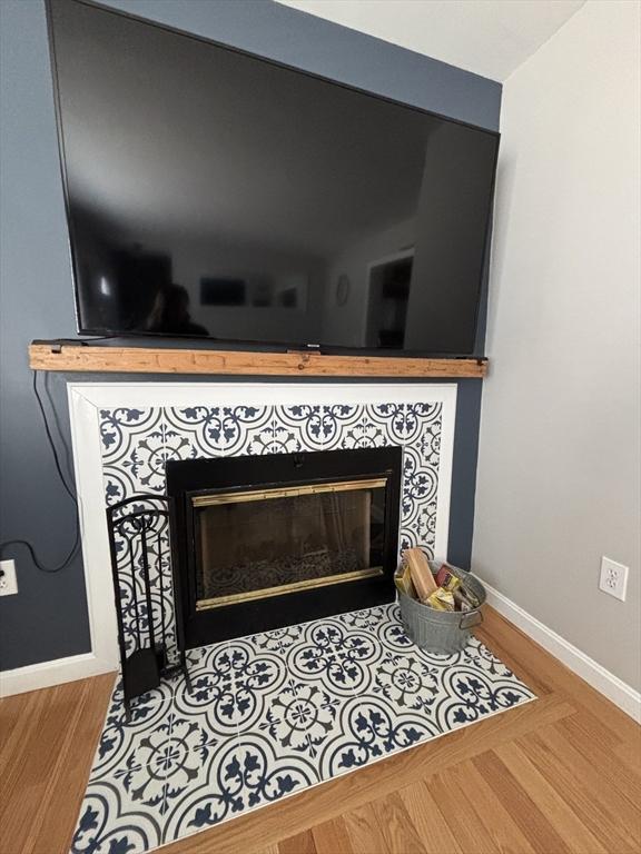 interior details with a fireplace, baseboards, and wood finished floors