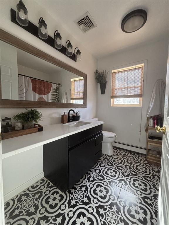 bathroom with visible vents, toilet, tile patterned flooring, baseboard heating, and vanity