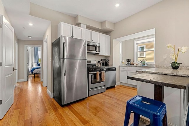 kitchen featuring appliances with stainless steel finishes, white cabinets, recessed lighting, and light wood-style flooring