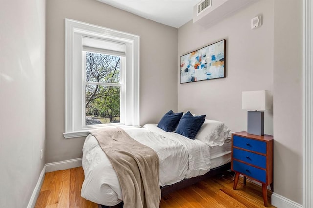 bedroom with baseboards, wood finished floors, and visible vents