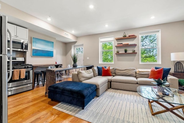 living room with recessed lighting, visible vents, a wealth of natural light, and light wood-style flooring