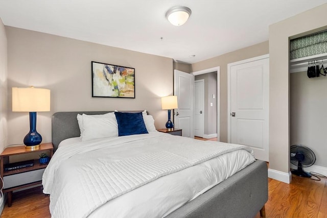 bedroom with baseboards, wood finished floors, and a closet