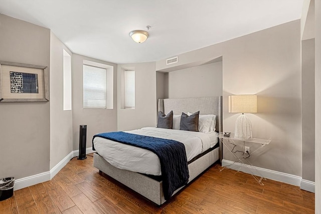 bedroom with baseboards, wood finished floors, and visible vents
