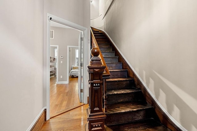 staircase with baseboards, wood finished floors, and visible vents
