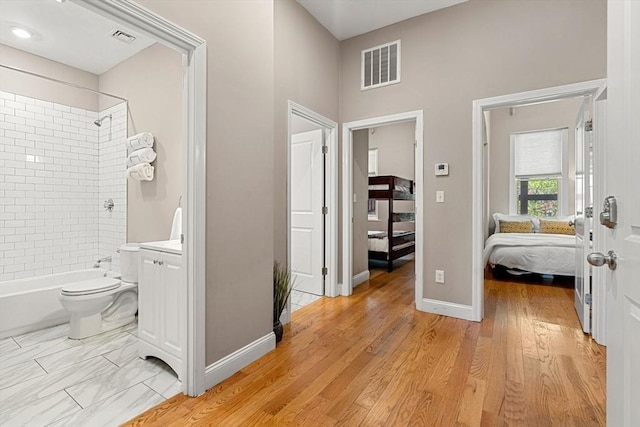 hallway with baseboards, visible vents, and light wood-style floors