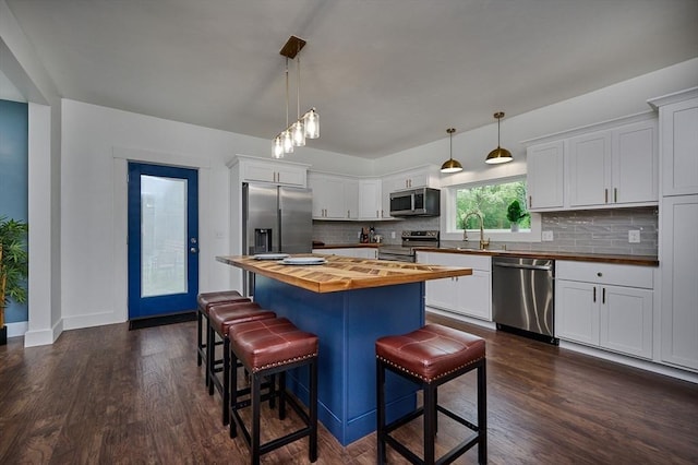 3030 Main St, Palmer, MA 01009 - kitchen with butcher block countertops, appliances with stainless steel finishes, tasteful backsplash, a kitchen bar, and dark wood-style floors