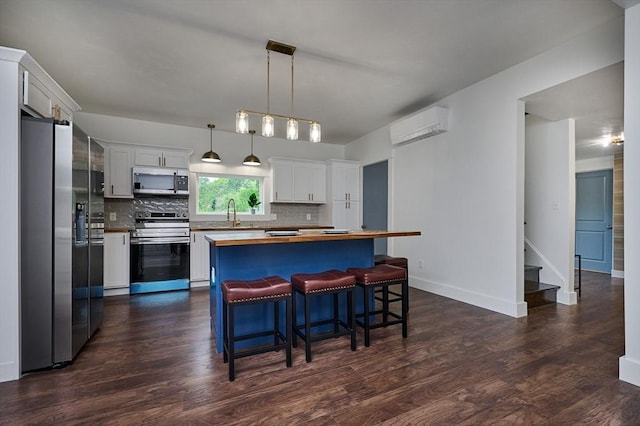 3030 Main St, Palmer, MA 01009 - kitchen featuring appliances with stainless steel finishes, an AC wall unit, butcher block countertops, white cabinets, and decorative backsplash