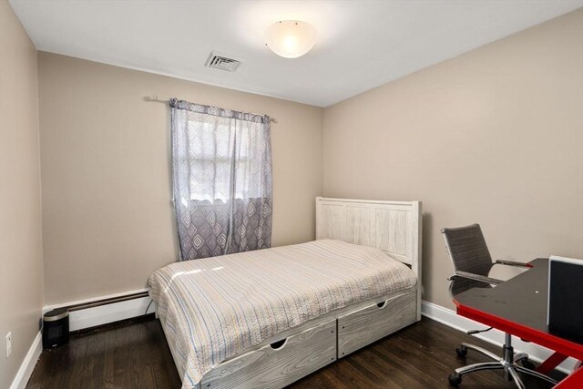 bedroom with baseboards, a baseboard heating unit, wood finished floors, and visible vents