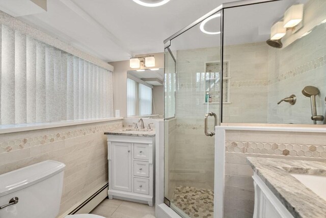 bathroom featuring tile patterned flooring, vanity, toilet, tile walls, and a stall shower