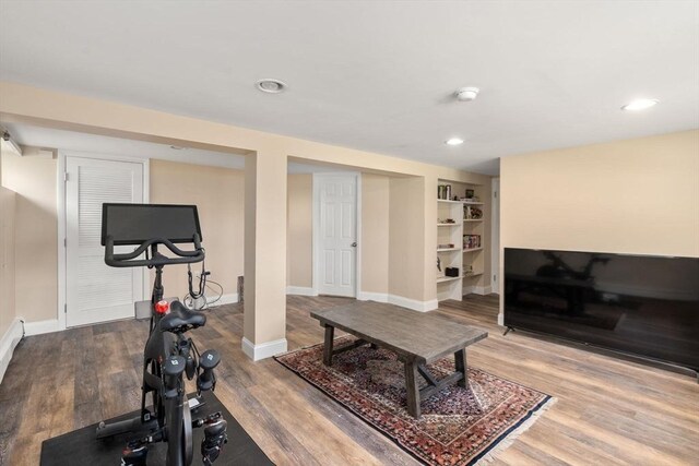 exercise area with built in shelves, baseboards, recessed lighting, and wood finished floors