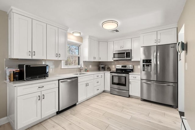 kitchen with light countertops, stainless steel appliances, visible vents, and a sink