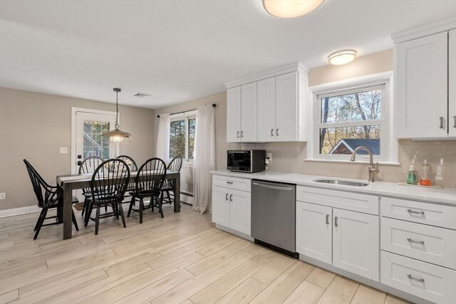 kitchen with white cabinets, appliances with stainless steel finishes, a sink, light wood-type flooring, and backsplash