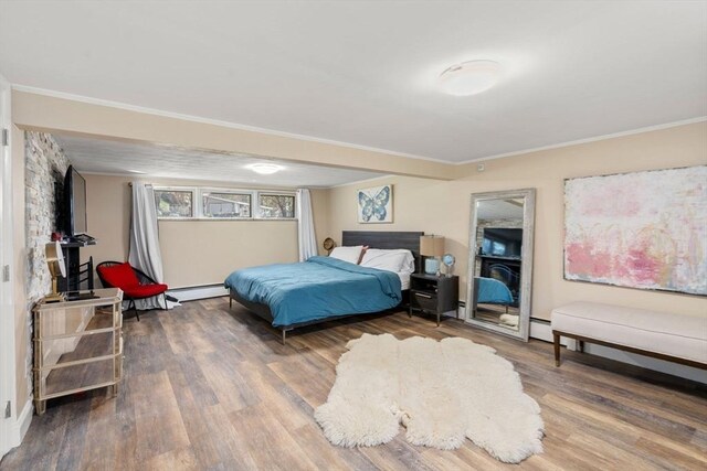 bedroom with ornamental molding, wood finished floors, and baseboard heating