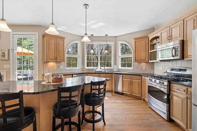 kitchen with stainless steel appliances, a breakfast bar, light wood finished floors, and tasteful backsplash