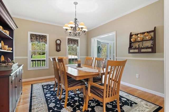 dining area featuring crown molding, baseboards, light wood-style flooring, and a notable chandelier