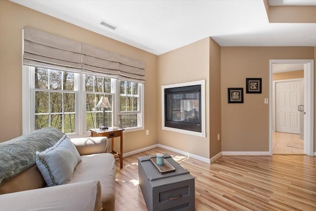 living area featuring baseboards, light wood-type flooring, and visible vents