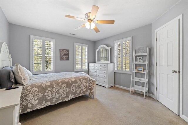 bedroom featuring light colored carpet, baseboards, visible vents, and ceiling fan