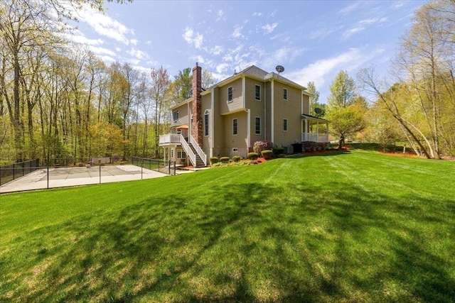 rear view of property featuring a wooden deck, fence, a chimney, stairs, and a yard