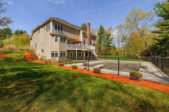 back of property with fence, a wooden deck, stairway, a chimney, and a lawn