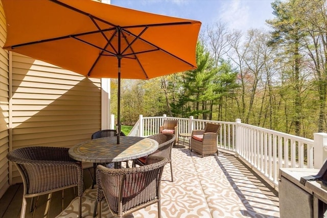 wooden deck with a forest view and outdoor dining space