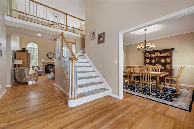 dining room with a fireplace, stairs, wood finished floors, and a chandelier