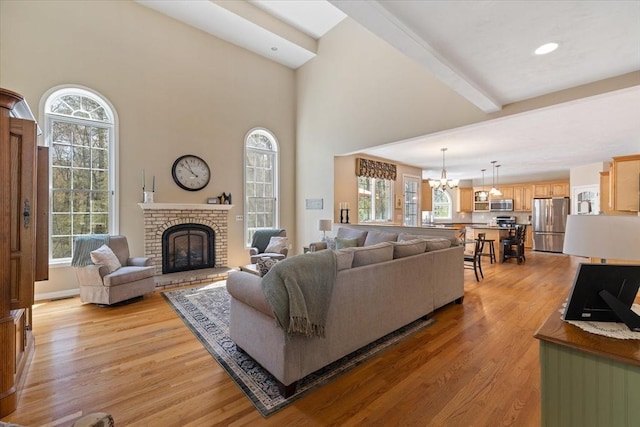 living room with plenty of natural light, light wood finished floors, a chandelier, and a fireplace