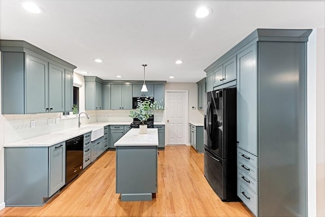 15 Pilgrim Rd, Mansfield, MA 02048 - kitchen with black appliances, a kitchen island, light countertops, a sink, and light wood-type flooring