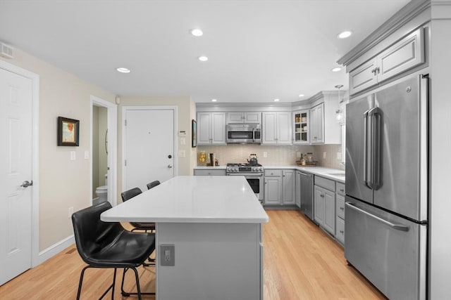 94 Mill Pond Unit 94, North Andover, MA 01845 - kitchen with high end appliances, gray cabinets, light wood-type flooring, a kitchen island, and tasteful backsplash