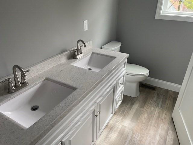 25 Ash St, Webster, MA 01570 - bathroom featuring toilet, double vanity, wood finished floors, and baseboards
