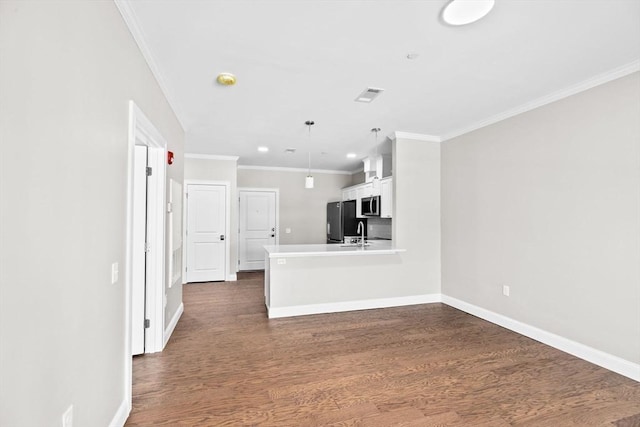 kitchen featuring baseboards, stainless steel microwave, dark wood-style flooring, freestanding refrigerator, and crown molding