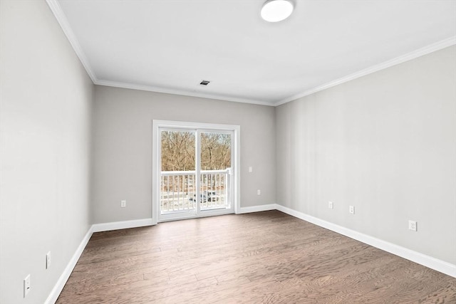 unfurnished room with ornamental molding, wood finished floors, visible vents, and baseboards