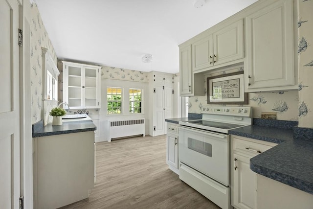 36 Uncle Barneys Rd, Dennis, MA 02670 - kitchen featuring radiator, white electric range, dark countertops, light wood-style floors, and wallpapered walls